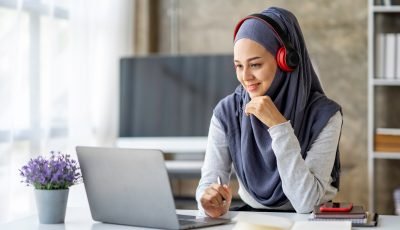 Muslim businesswoman wearing a hijab looks at camera working Online Tutoring. Young Muslim woman tea
